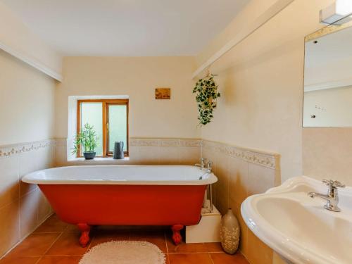 a bathroom with a red tub and a sink at 4 Bed in Dartmoor National Park 49535 in Sampford Courtenay