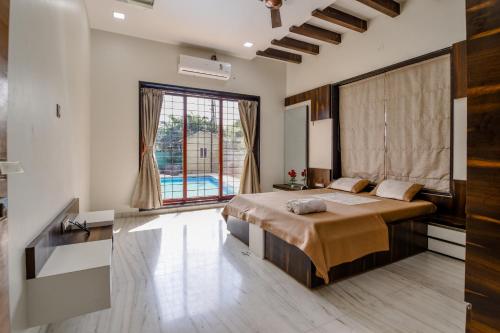 a bedroom with a bed and a large window at Villan Villa Luxurious Mountain View Biggest Pool in Lonavala