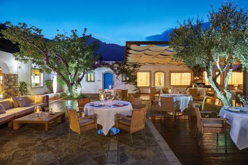 a restaurant with tables and couches and trees at Elounda Beach Hotel & Villas, a Member of the Leading Hotels of the World in Elounda