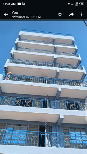 a tall white building with balconies on it at one bedroom in oj town ruiru in Kiambu