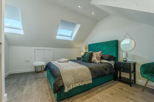 a bedroom with a green bed and a mirror at Stylish Homes W/ Fast Transport Links To London in Bromley