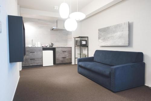 a living room with a blue couch and a kitchen at HOTEL MASTAY jingumichi in Kyoto