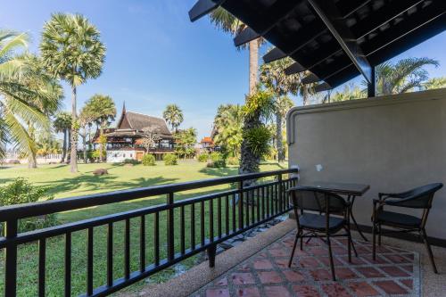 a balcony with two chairs and a table and a house at The Hotspring Beach Resort & Spa - SHA Extra Plus in Natai Beach