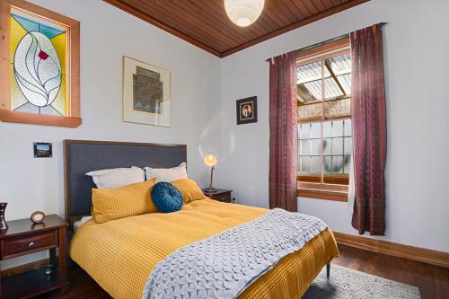 a bedroom with a bed with a yellow blanket and a window at Aranui palms - Mapua Holiday Home in Mapua