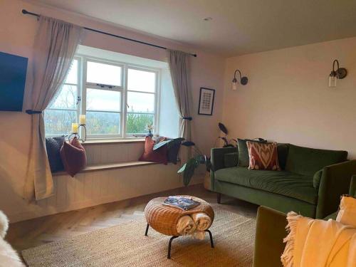 uma sala de estar com um sofá verde e uma janela em Boutique, weaver’s cottage. Views em Bradford on Avon