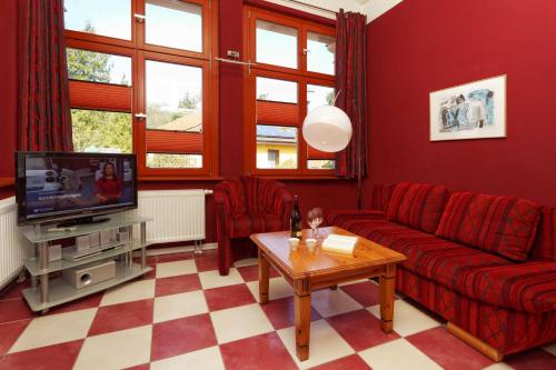 a living room with a red couch and a tv at Villa Maria Wohnung 01 in Ostseebad Koserow