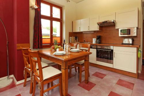 Villa Maria Wohnung 02 في أوستسيباد كوسيروف: مطبخ مع طاولة خشبية وبعض الكراسي