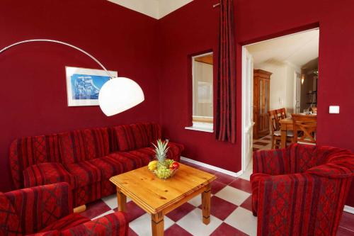 salon z 2 czerwonymi krzesłami i stołem w obiekcie Villa Maria Wohnung 09 w Koserowie