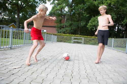 two young boys are playing with a soccer ball at Camping de Haer in Ootmarsum