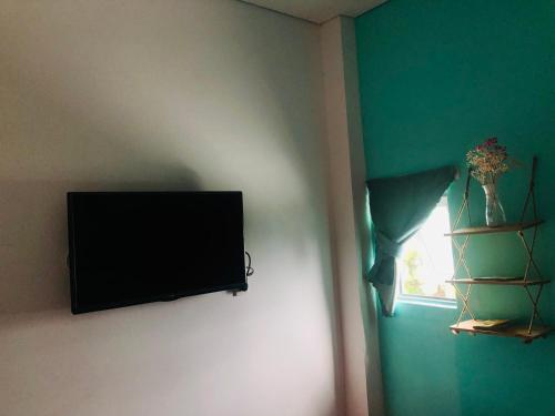 TV de pantalla plana colgada en una pared junto a una ventana en Như Ngọc Motel, en Cà Mau