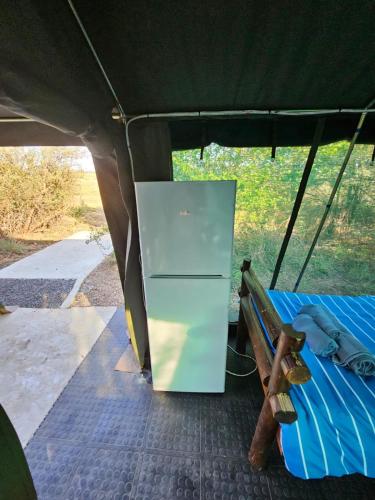 a refrigerator in the back of a tent with a bench at Merry Mongoose Riverside Tent in Skeerpoort