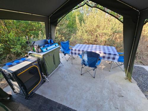 a tent with a table and chairs and a tv at Merry Mongoose Riverside Tent in Skeerpoort