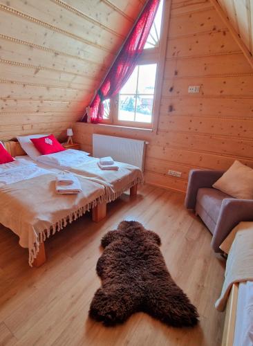 a attic room with two beds and a rug at Góralski Domek Łopatówka z kominkiem i Banią - Jacuzzi! in Murzasichle