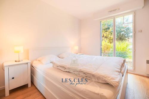 une chambre blanche avec un lit avec une fenêtre dans l'établissement PARK AVENUE - Grand T2 centre ville, à Le Touquet-Paris-Plage