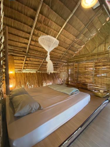 a bed in a room with a thatch roof at Royal mountain lake view in Ratchaburi