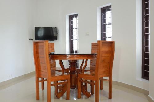 a wooden table with chairs and a television on it at HILLFORT HOMESTAY in Vagamon