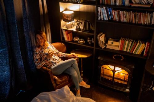 a woman sitting in a chair next to a fireplace at Hôtel Lilybloom in Le Havre