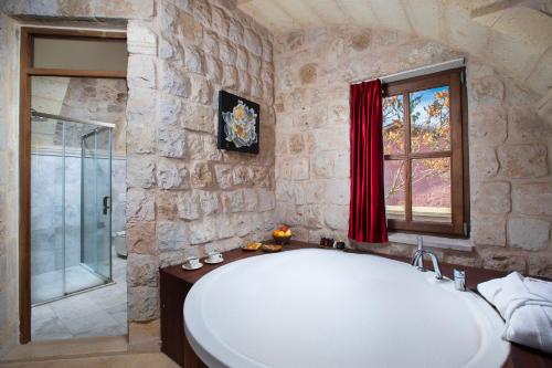 een groot wit bad in een stenen badkamer met een raam bij Woox Cappadocia in Nevsehir