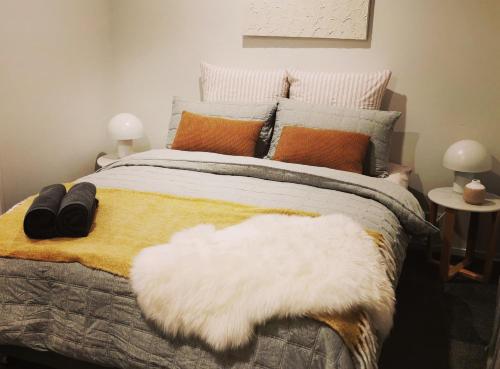 een slaapkamer met een bed met een witte deken en kussens bij Ralph's Little Cottage in Christchurch