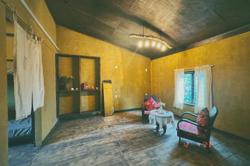 a room with yellow walls and a table and chairs at Maison de Hill Home in Dồng Văn