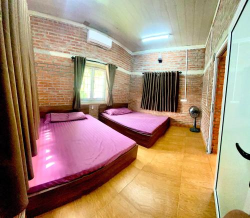 duas camas num quarto com uma parede de tijolos em Lều biệt thự em Hanói