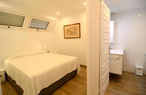 レスカラにあるApartamentos Passeig Del Marの白いベッドルーム(ベッド1台付)