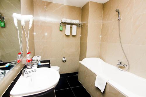 a bathroom with a sink and a toilet and a tub at Parkside Mandarin Hotel Pekalongan in Pekalongan