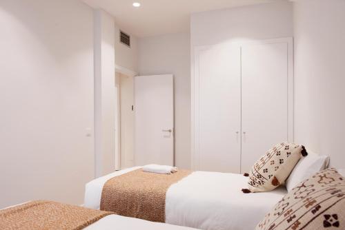 2 bedden in een witte kamer met witte muren bij Bravissimo Ferreries Velles, with 2 bedrooms in Girona