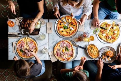 Un gruppo di persone seduti intorno a un tavolo a mangiare pizza di Hôtel Lilybloom a Le Havre