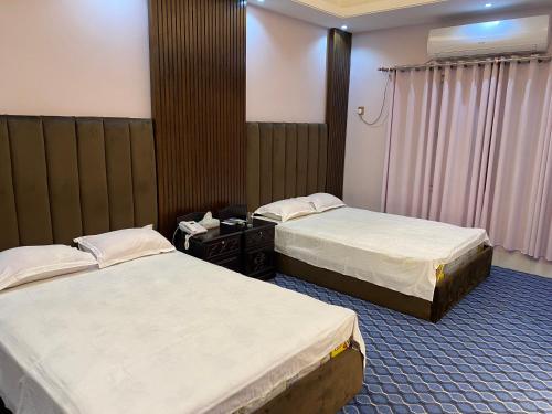 a hotel room with two beds and a window at Hotel Grand Akther Sylhet in Sylhet