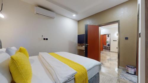 a bedroom with a bed with a yellow blanket on it at YANNA APARTMENT BY KHALIQUES in Abuja