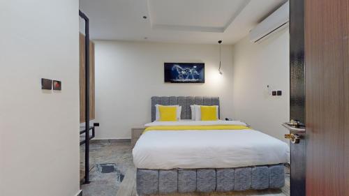 a bedroom with a large bed with yellow pillows at YANNA APARTMENT BY KHALIQUES in Abuja