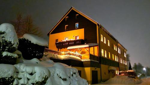 a large building with lights on in the snow at Ferienwohnungen "Am Schlössel" in Kurort Oberwiesenthal