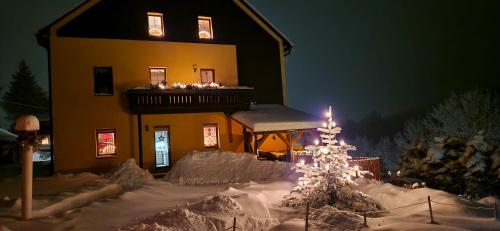 a snow covered house with a christmas tree in front of it at Ferienwohnungen "Am Schlössel" in Kurort Oberwiesenthal
