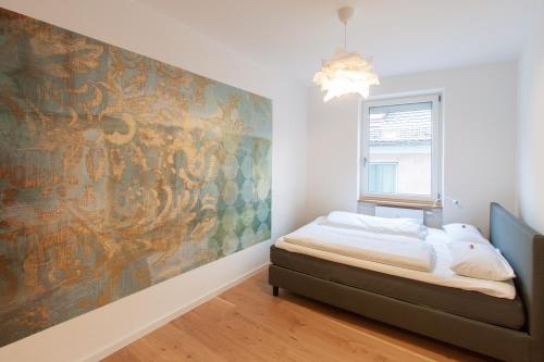 維爾茨堡的住宿－Juliusliving - modernes Wohnen an der Juliuspromenade，卧室配有一张床,墙上挂有绘画作品