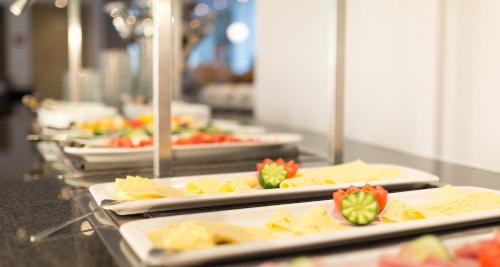 Una línea de buffet con varias bandejas de comida en Victor's Residenz-Hotel Berlin Tegel, en Berlín