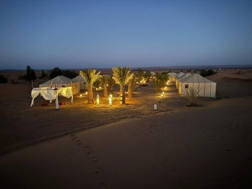 a group of tents in the desert at night at Nomads Luxury Camp Merzouga in Adrouine