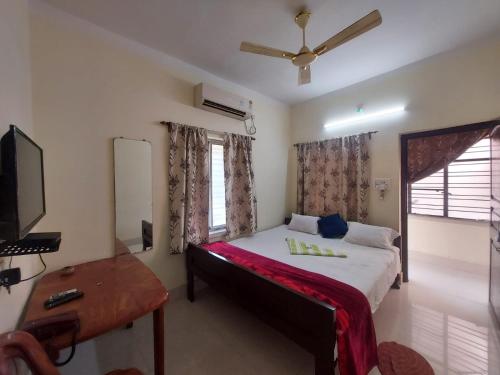 um quarto com uma cama, uma secretária e uma televisão em Rajlaxmi Resort - Pure Veg em Bolpur