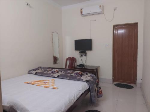 Schlafzimmer mit einem Bett und einem Schreibtisch mit einem TV in der Unterkunft Rajlaxmi Resort - Pure Veg in Bolpur