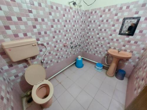 uma casa de banho em azulejos cor-de-rosa com um WC e um lavatório. em Rajlaxmi Resort - Pure Veg em Bolpur