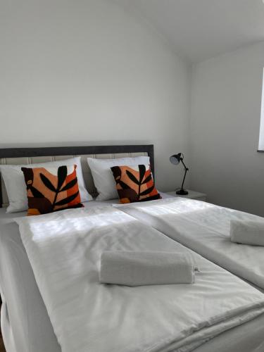 een groot wit bed met oranje en zwarte kussens bij Apartman Dolly Bell in Kotor-Varoš