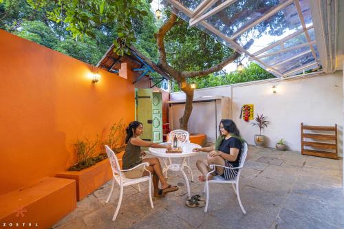 two women sitting at a table under a tree at Zostel Pondicherry, Auroville Road in Pondicherry