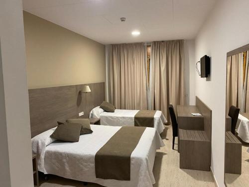 a hotel room with two beds and a desk at Ca La Maria in Tordera
