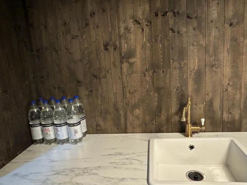 two bottles of water sitting on a counter next to a sink at Beautiful Cabin by Mjøsa. in Stange