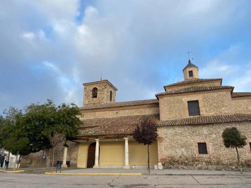 an old stone building with a tower and a church at Casa Las 7 Maravillas in Fuentidueña de Tajo