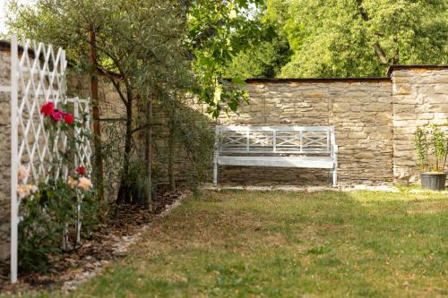 a white bench sitting in a yard next to a stone wall at Chalupa Kolowrat in Horka