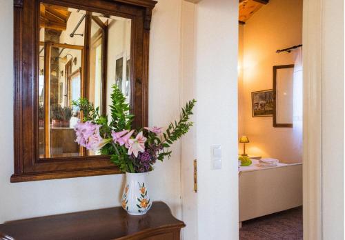 a vase with flowers on a table in front of a mirror at Palaiopolis house in Avlemonas