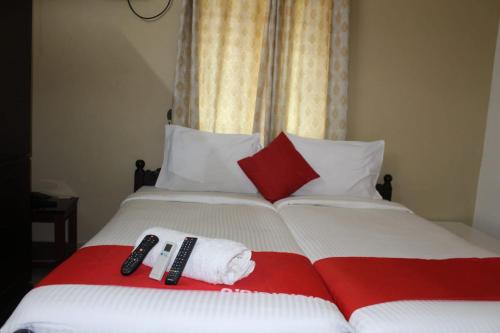 a bed with two remotes and towels on it at Malgudi Holidays in Kannur