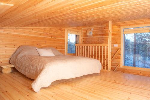 a bedroom in a log cabin with a bed at Rahkis Lodge Saariselkä in Saariselka