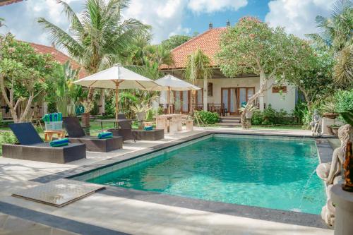 a pool with chairs and umbrellas next to a house at Bingin Garden Uluwatu in Uluwatu